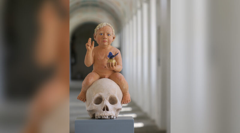 Terrakottafigur eines Kindes, dass auf einem Schädelknochen sitzt