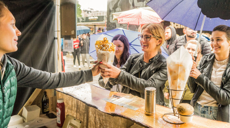 Eine Standverkäuferin reicht einer Kundin Essen aus dem Foodtruck.