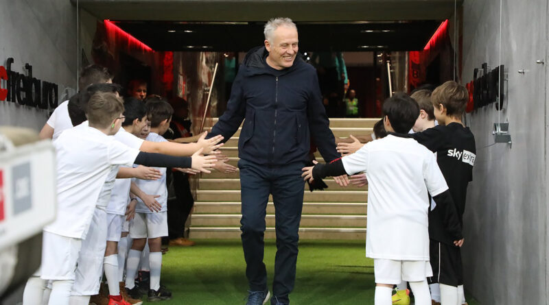 Christian Streich, der ehemalige Trainer des SC Freiburg begrüßt Kinder in Fußballkleidung