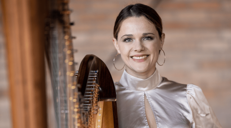 Die festlich gekleidete Musikerin Annalena Storch mit einer Harfe