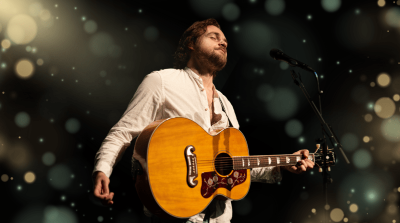 Der Sänger Patrick Snow mit einer Gitarre auf der Bühne